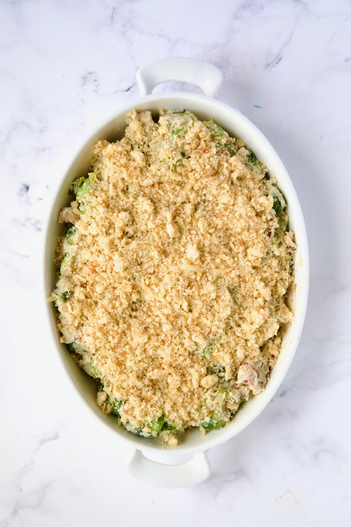 Brussels Sprouts Gratin fully assembled with breadcrumb topping in oval baking dish ready to bake.