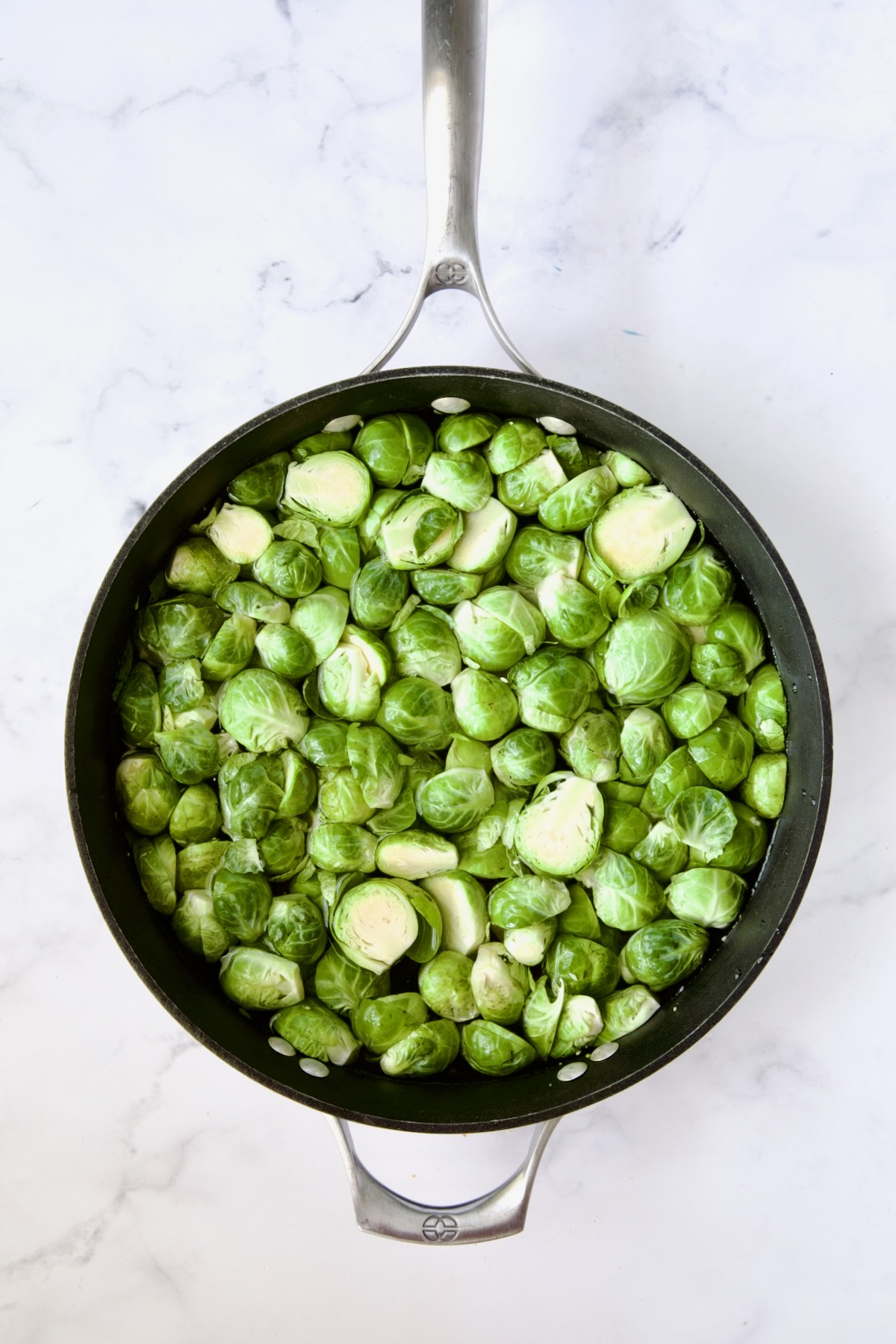 Brussels sprouts cut in half in nonstick skillet.