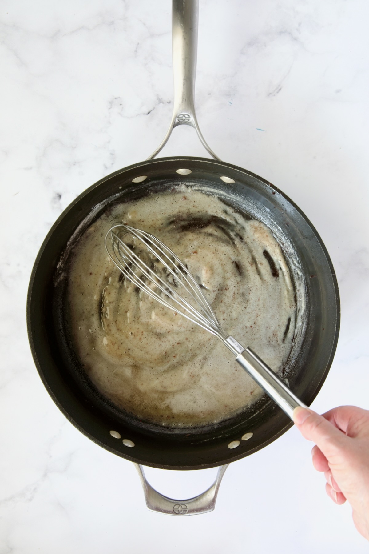 Flour being whisked into bacon drippings in nonstick skillet.