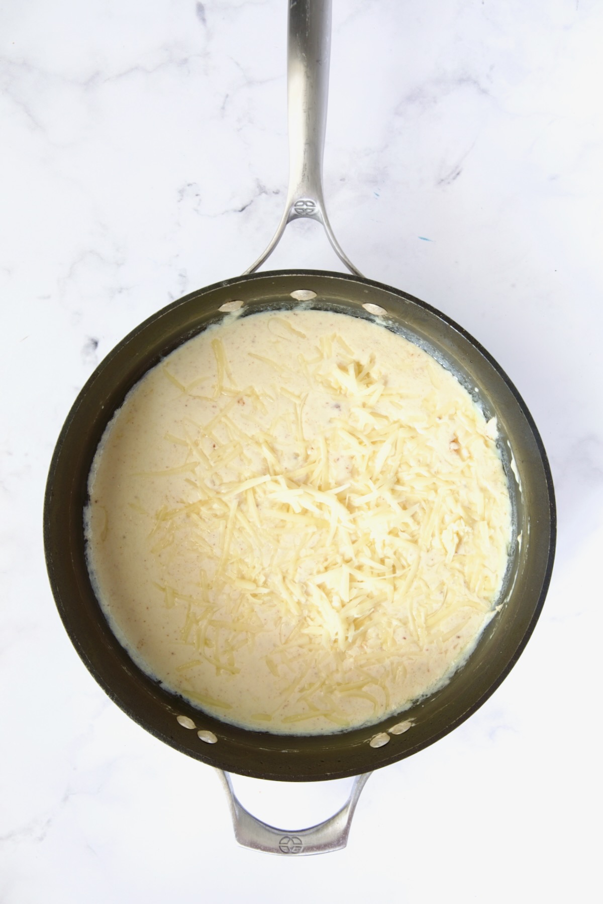 Cheese added to cream sauce in nonstick skillet.