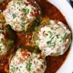 Three Italian Stuffed Peppers in deep white round baking dish.