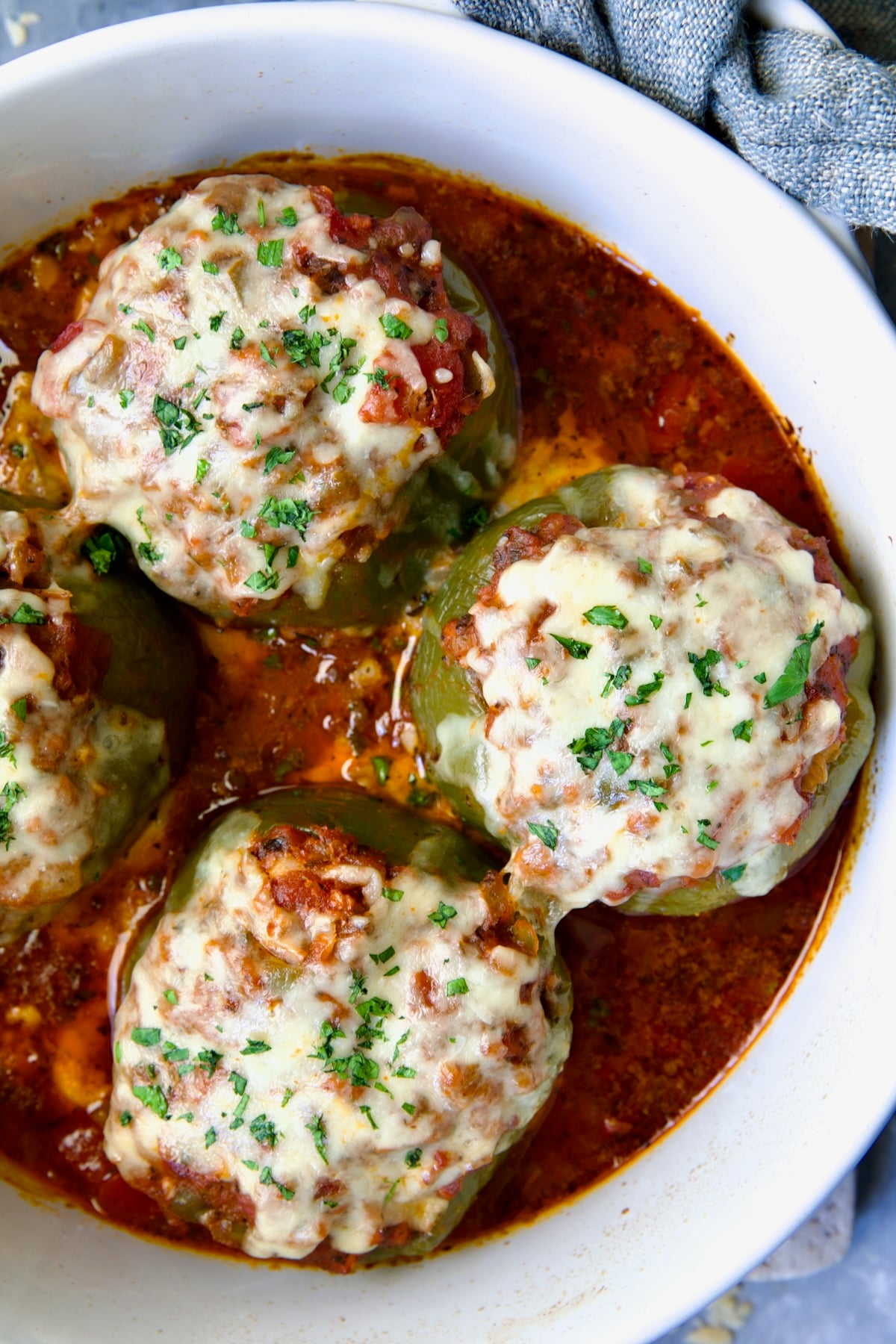 Three Italian Stuffed Peppers in deep white round baking dish.