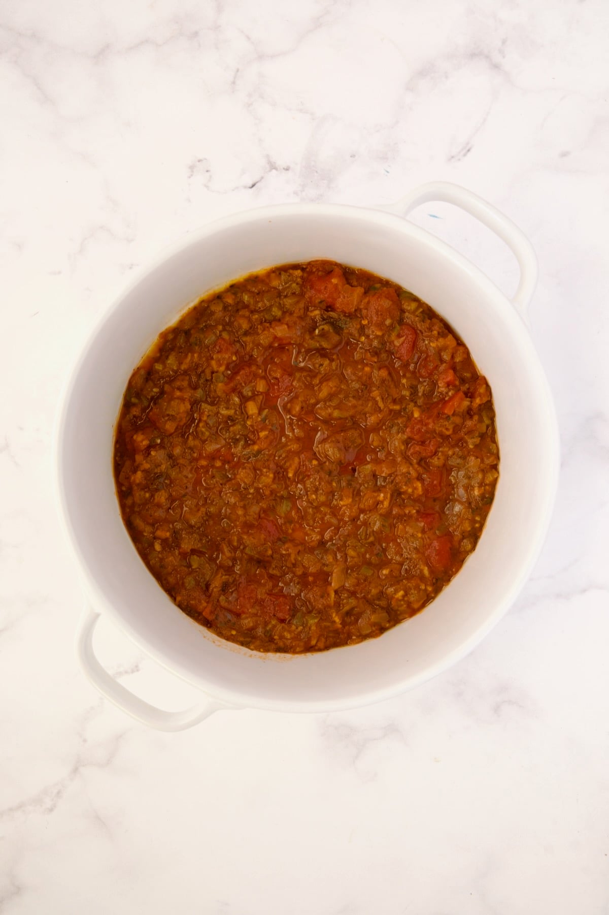 Tomato sauce in deep white round baking dish before bell peppers go in.