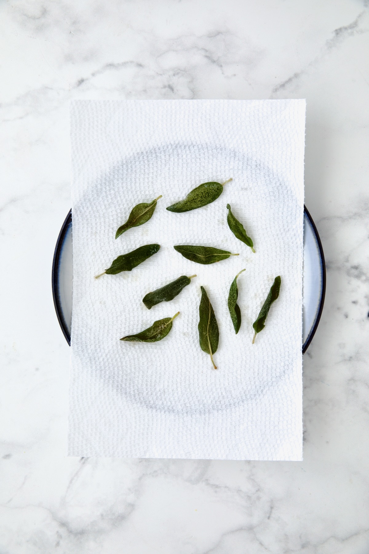 10 fried sage leaves on paper towel-lined plate.