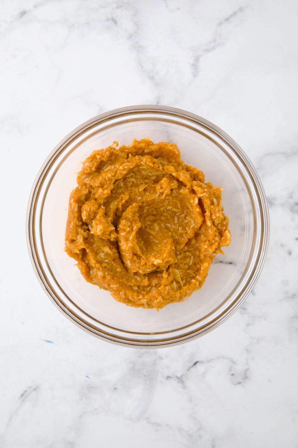 Pumpkin puree with parmesan cheese in glass bowl mixed together.