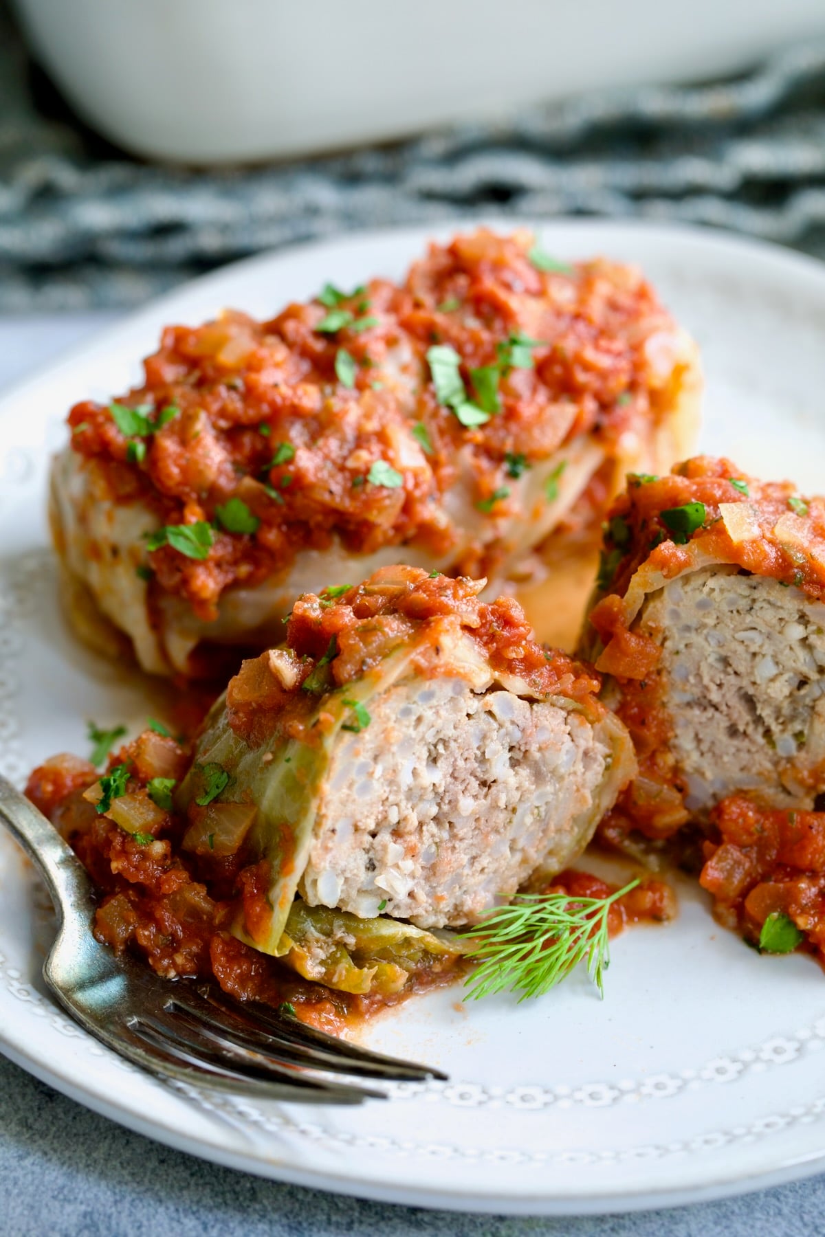 Polish Stuffed Cabbage roll cut in half to expose filling on white plate.