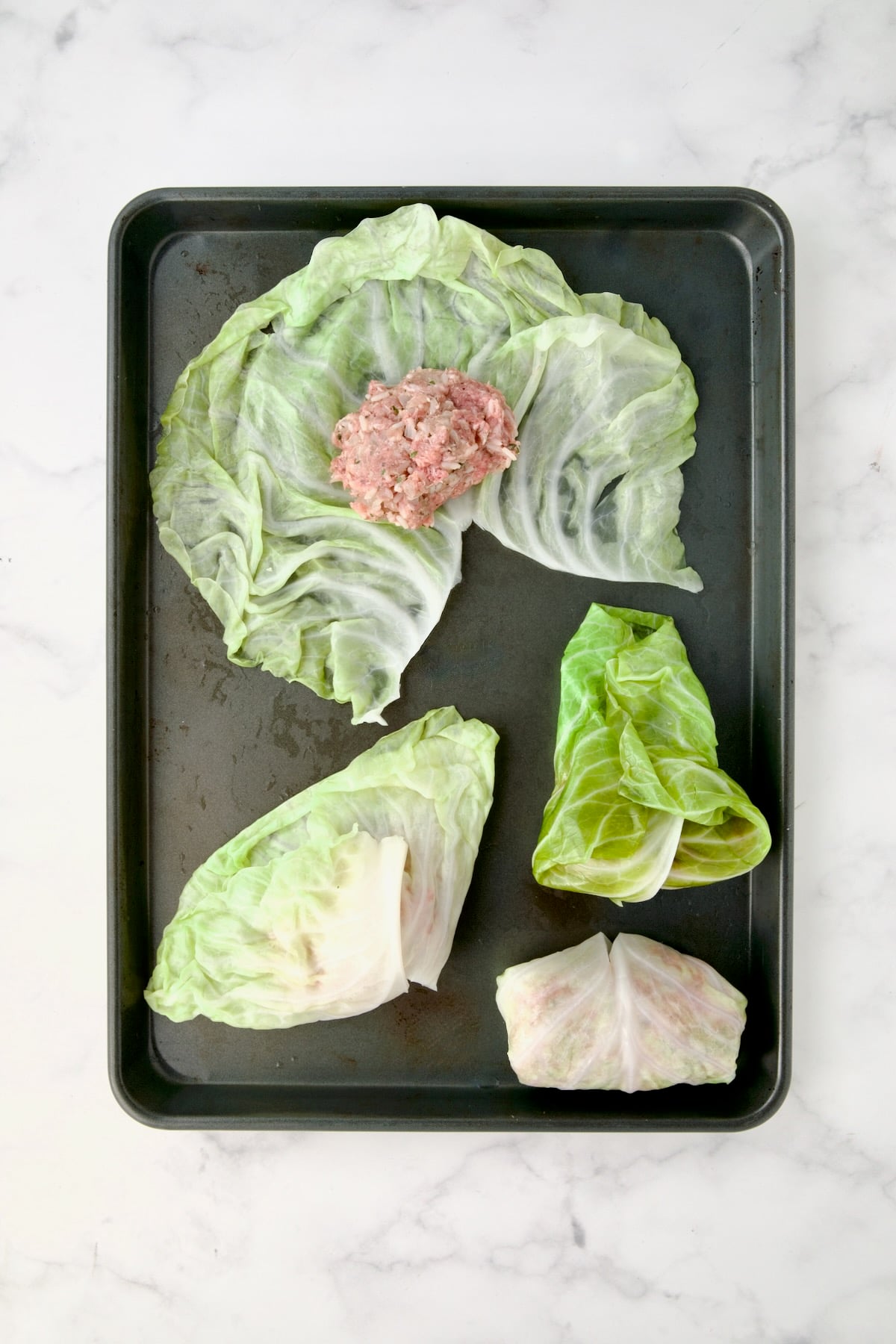 Steps demonstrating how to fill cabbage rolls: One unrolled with filling, one with bottom flaps brought over filling, another with sides tucked in and one fully rolled.