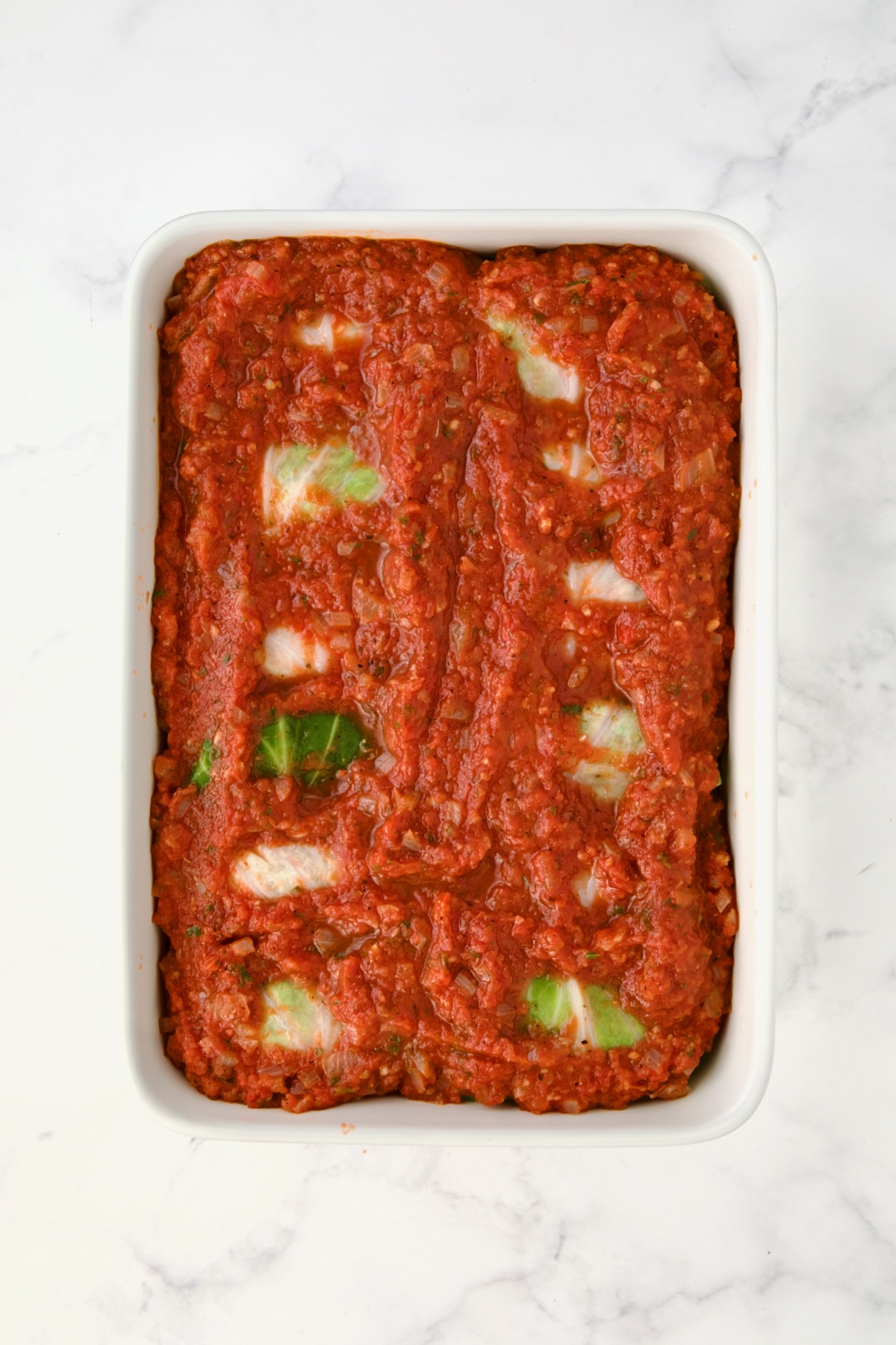 Sauced cabbage rolls ready to be baked.