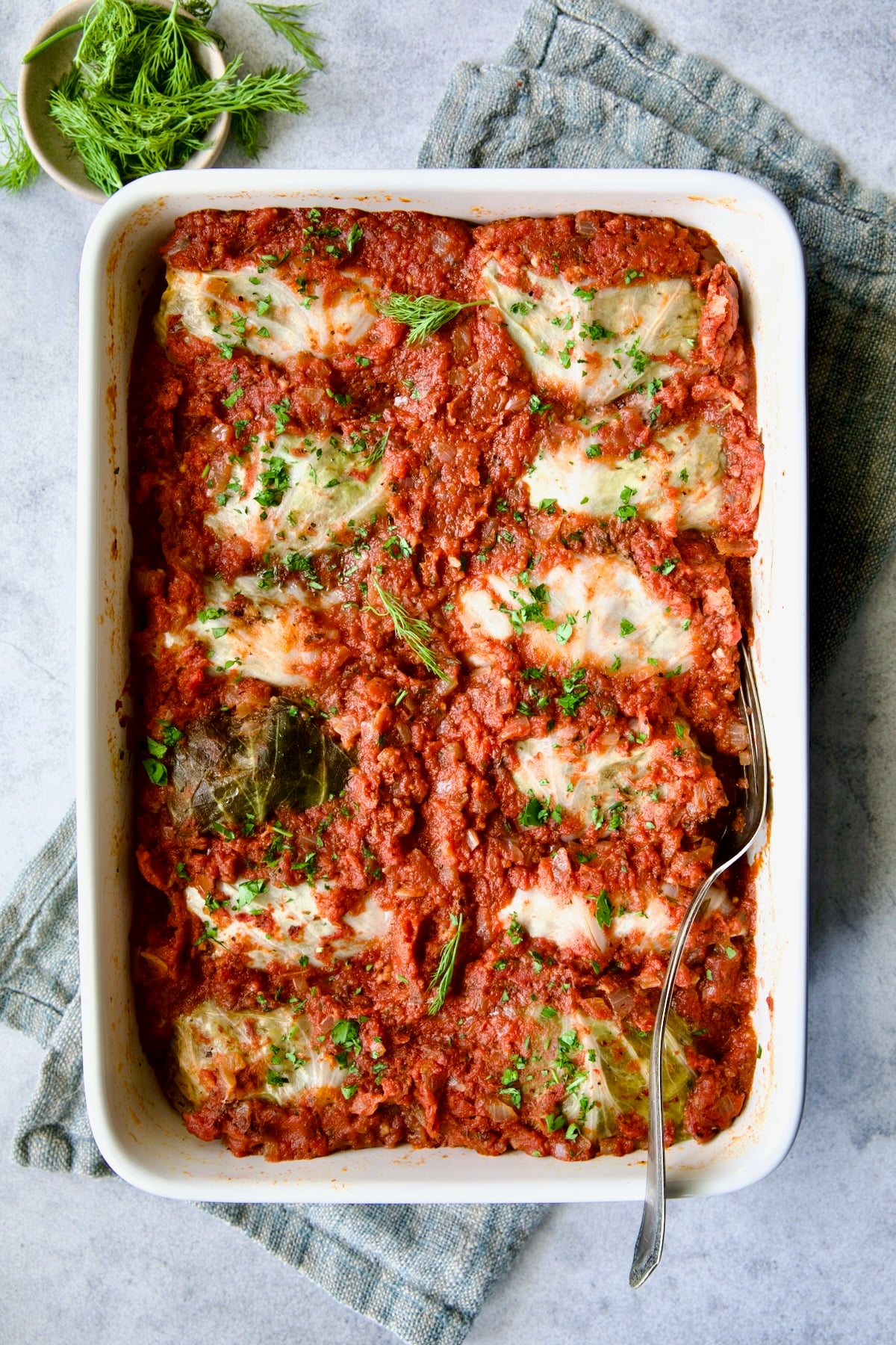 Baking dish full of Polish Stuffed Cabbage on blue napkin after being baked.