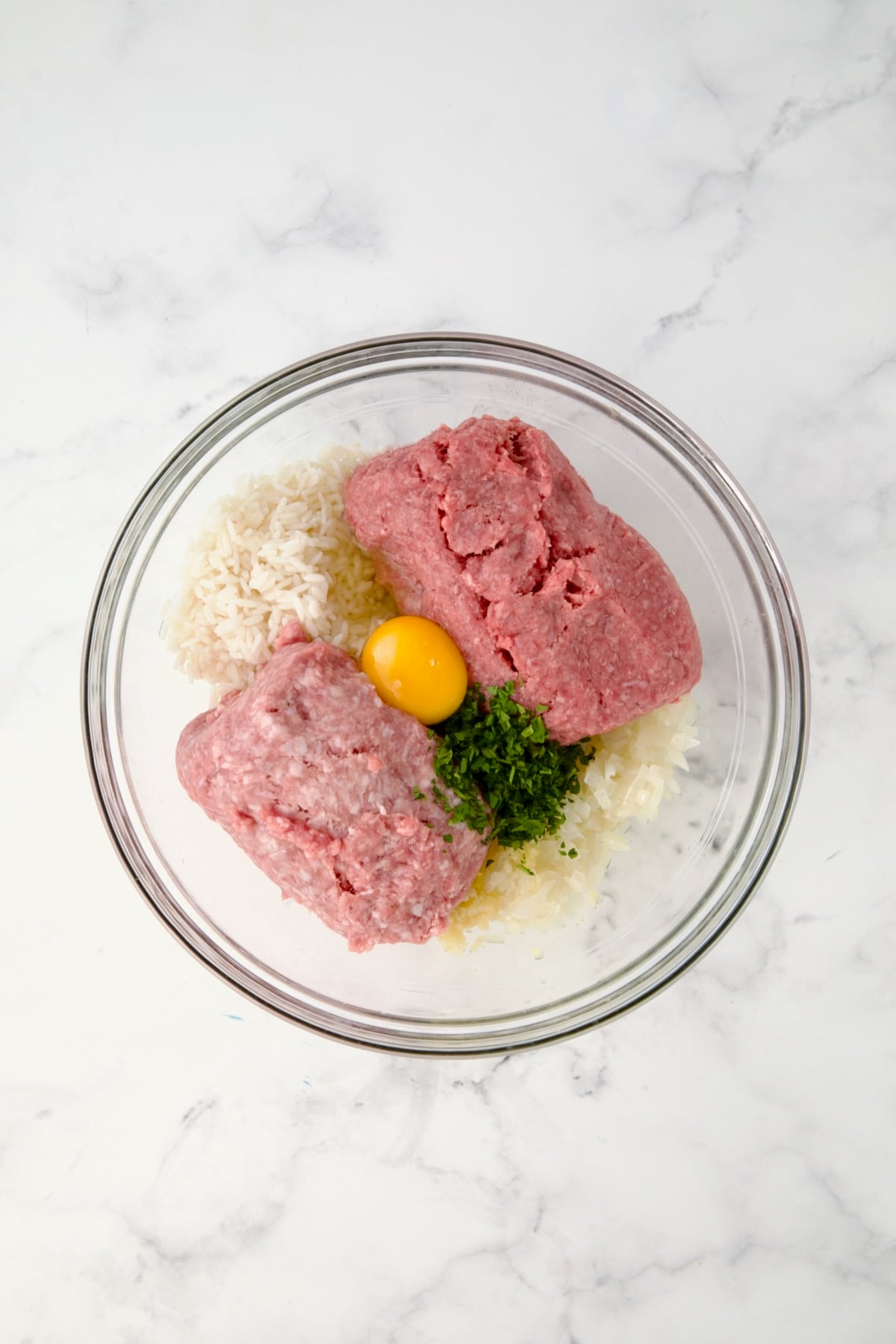 Filling for Polish Stuffed Cabbage rolls in glass bowl consisting of cooked rice, meats, egg, parsley and onion.