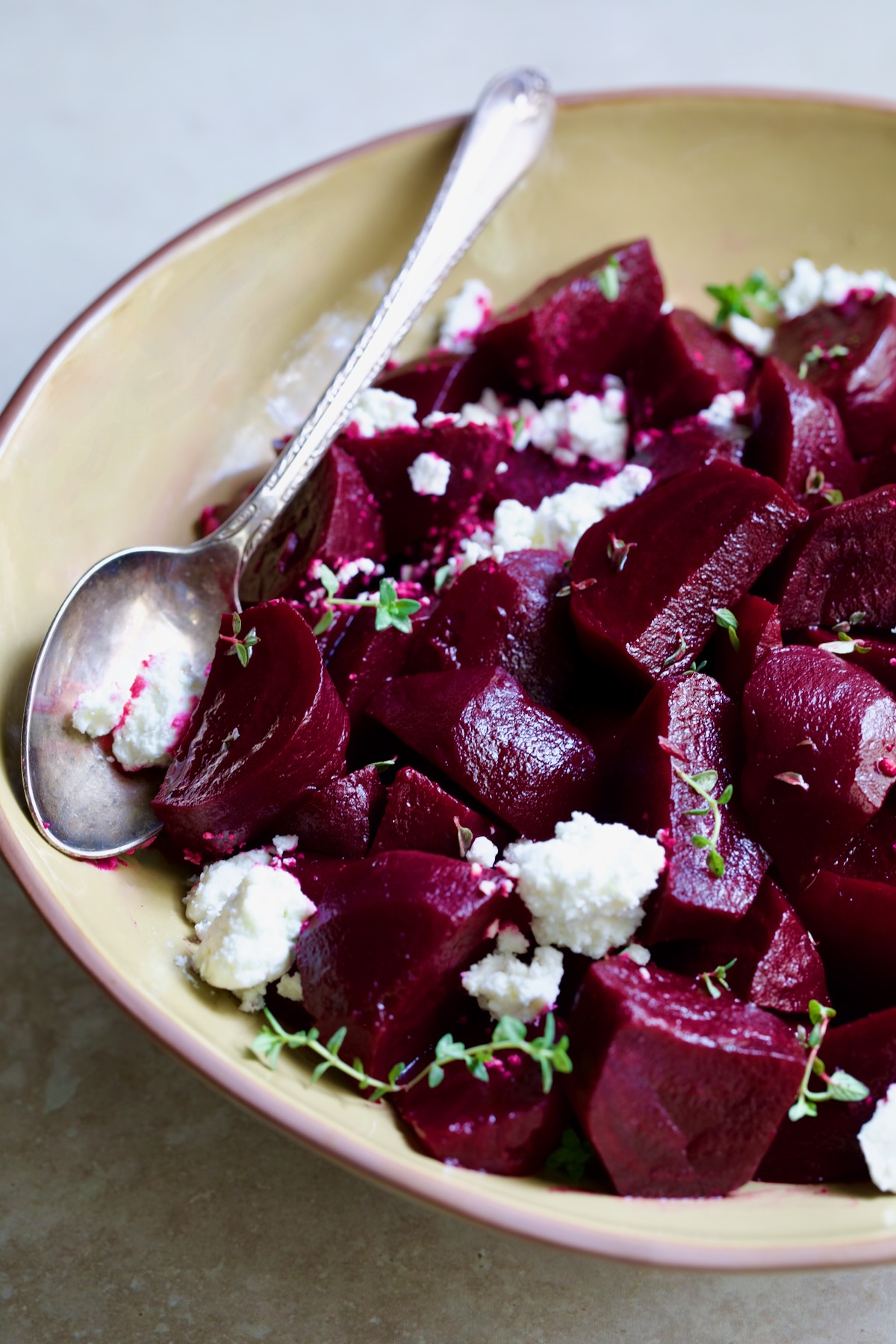 serving bowl with serving spoon sprinkled with goat cheese.