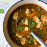 Sausage Spinach Tortellini Soup in white Dutch oven with soup ladle.