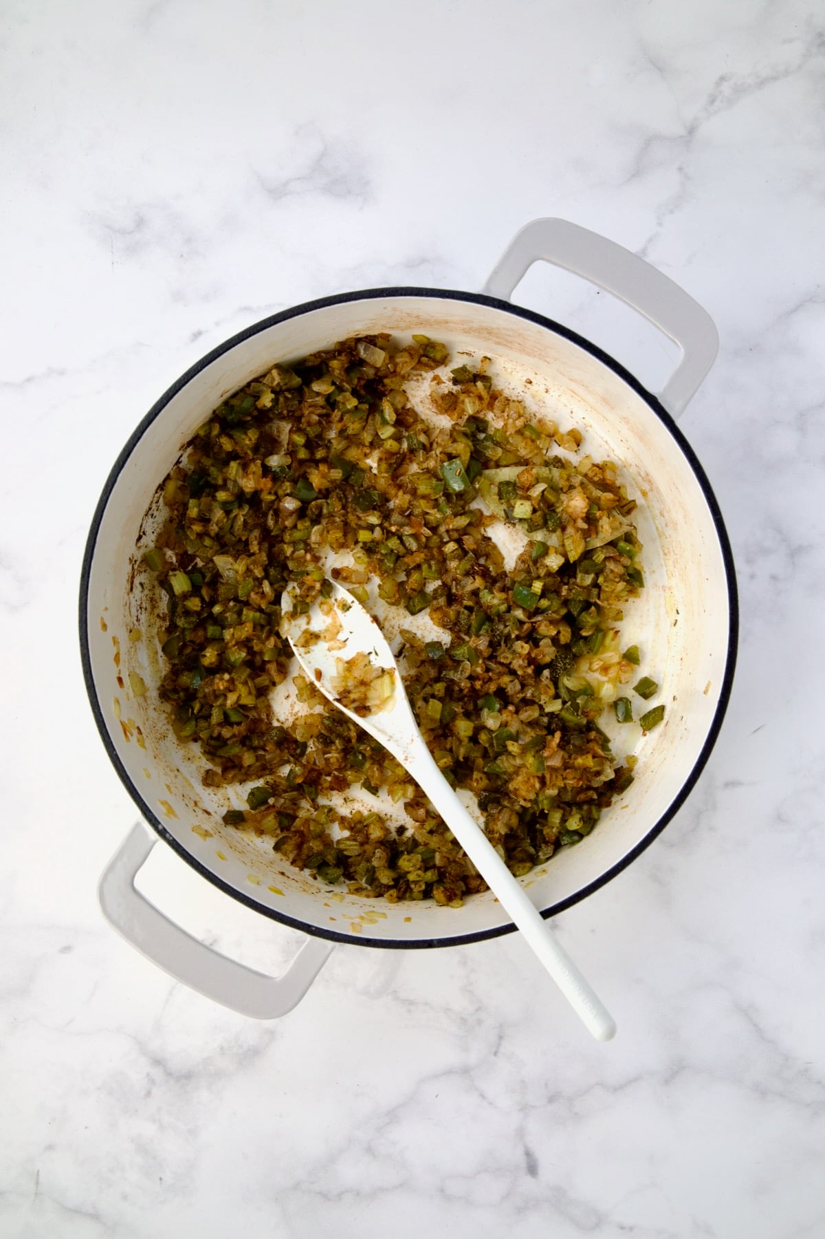 Cooked onions, celery and green bell pepper with Cajun seasoning, cayenne, thyme, garlic and bay leaf added and stirred together.