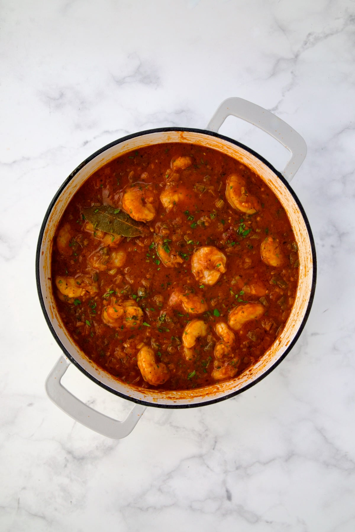 Finished Shrimp Creole with cooked shrimp in white enamel cast iron skillet.
