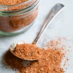 Spoon of Blackening Seasoning spilling over onto surface with jar in the background.
