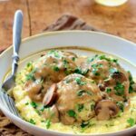 Chicken Meatballs Marsala with Parmesan Polenta in white bowl with fork.