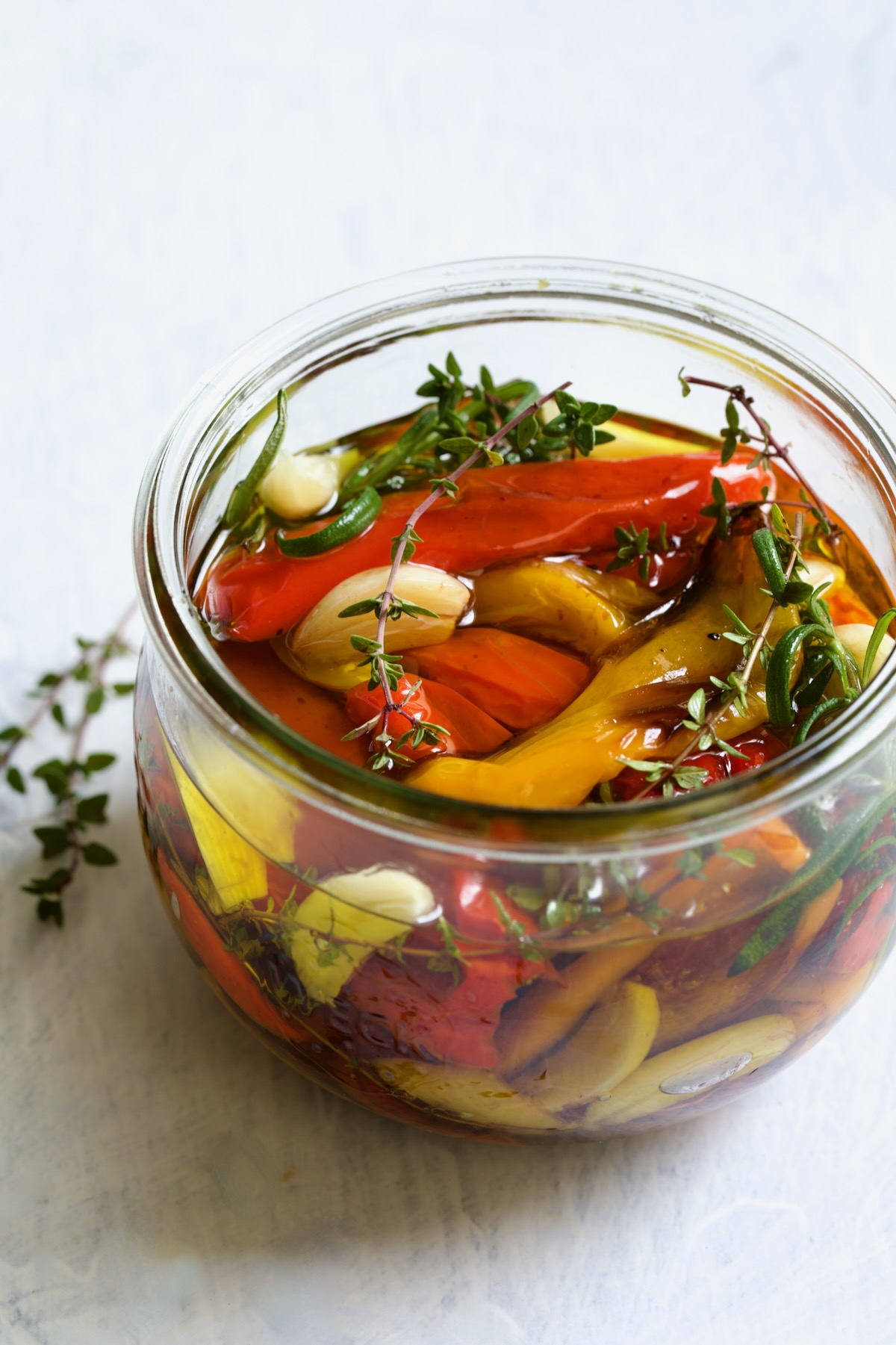 Roasted Mini Peppers in glass jar with fresh herbs and garlic.