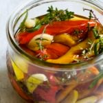 Roasted Mini Peppers in glass jar with fresh herbs and garlic.