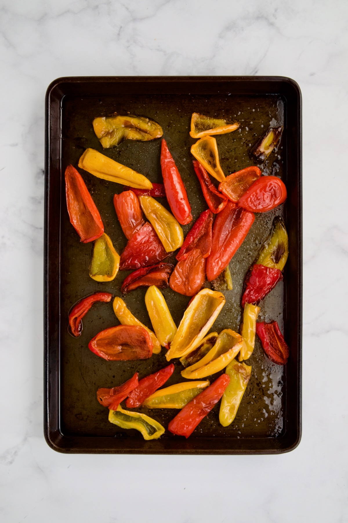 Roasted mini peppers on rimmed sheet pan after being roasted.