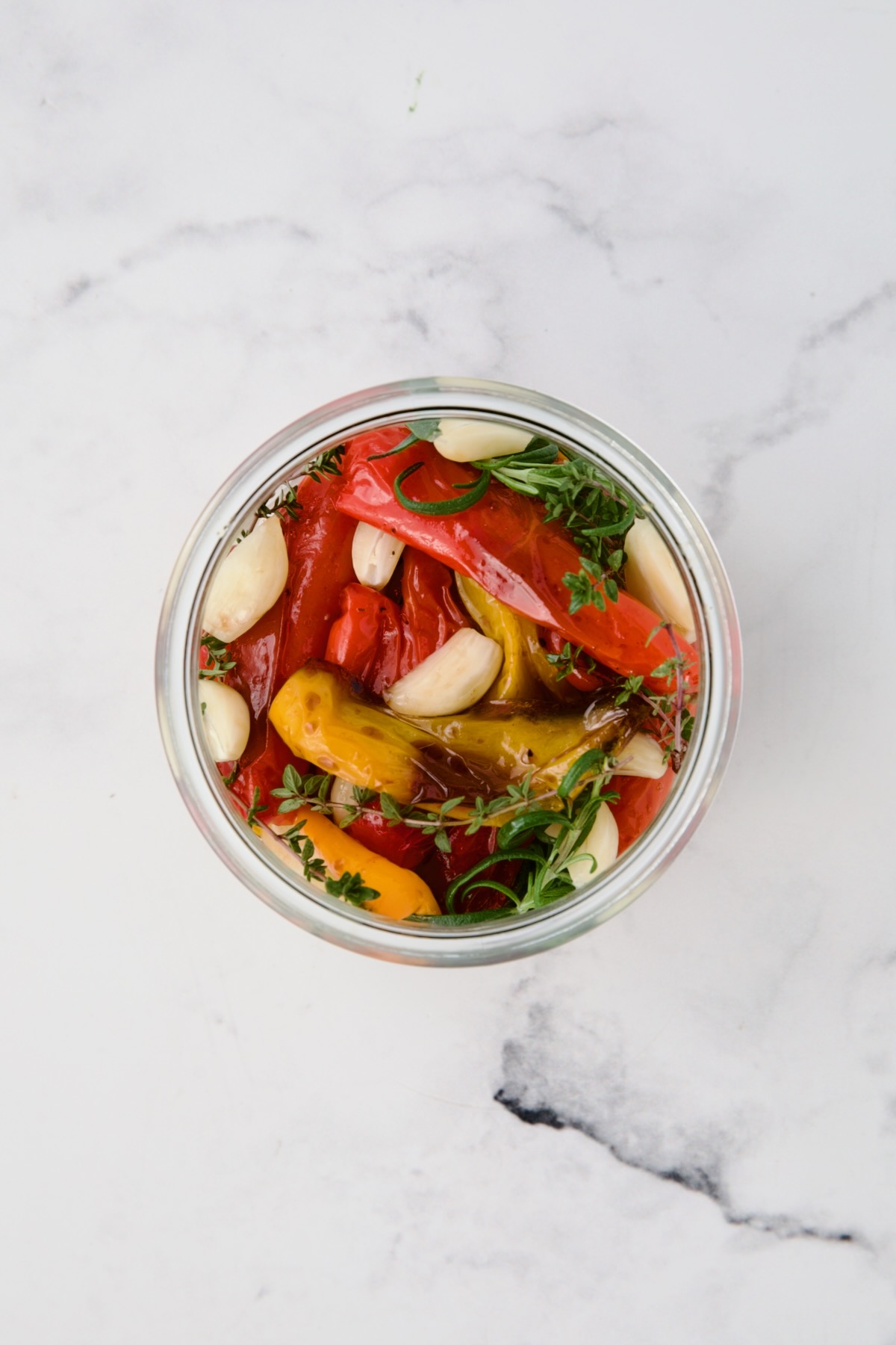 Roasted mini peppers in glass jar before olive oil is added.
