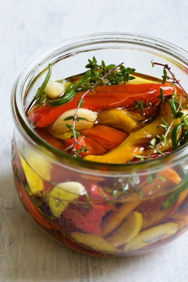 Roasted Mini Peppers in glass jar with fresh herbs and garlic.