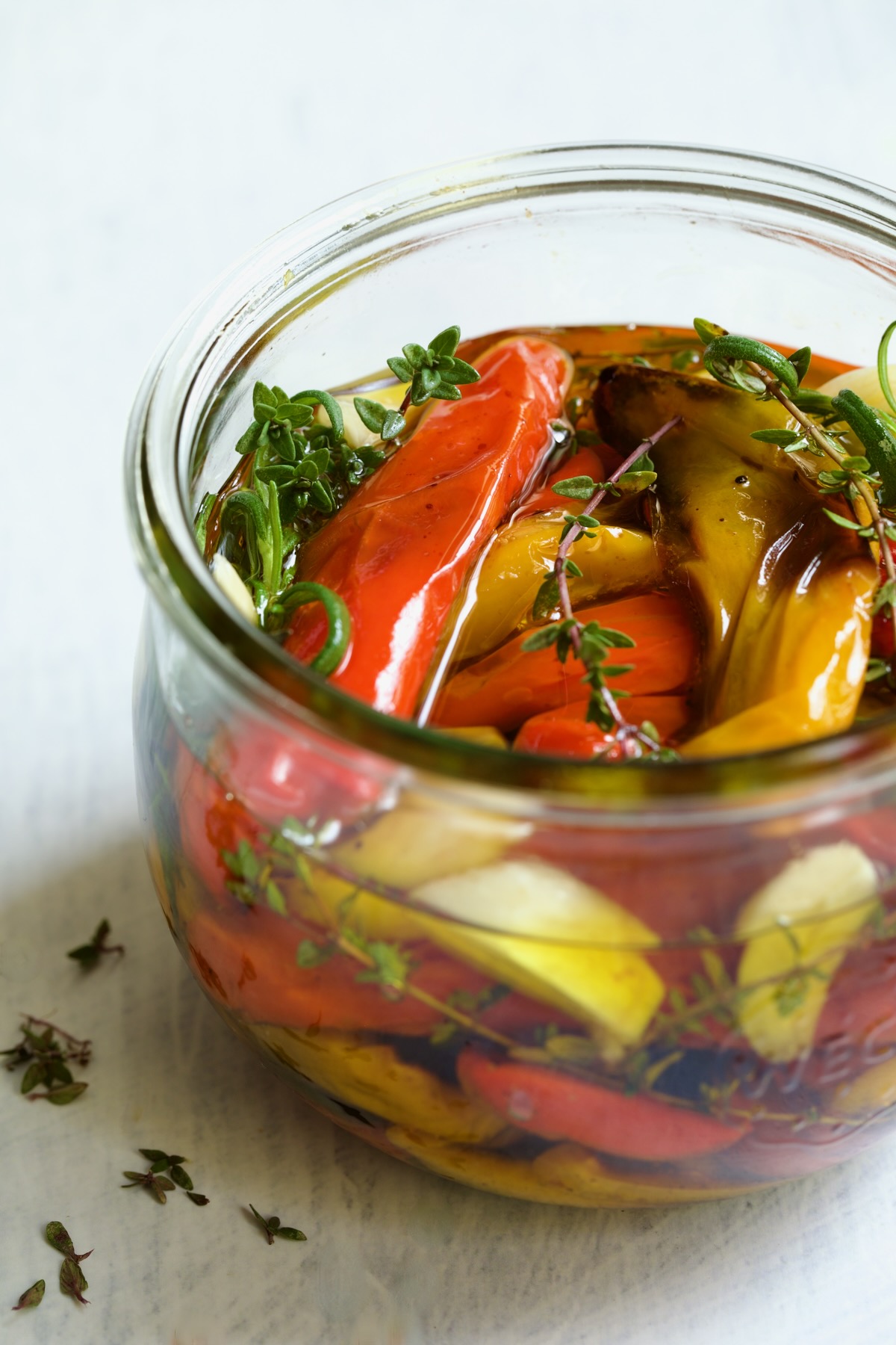 Roasted Mini Peppers in glass jar with fresh herbs and garlic.