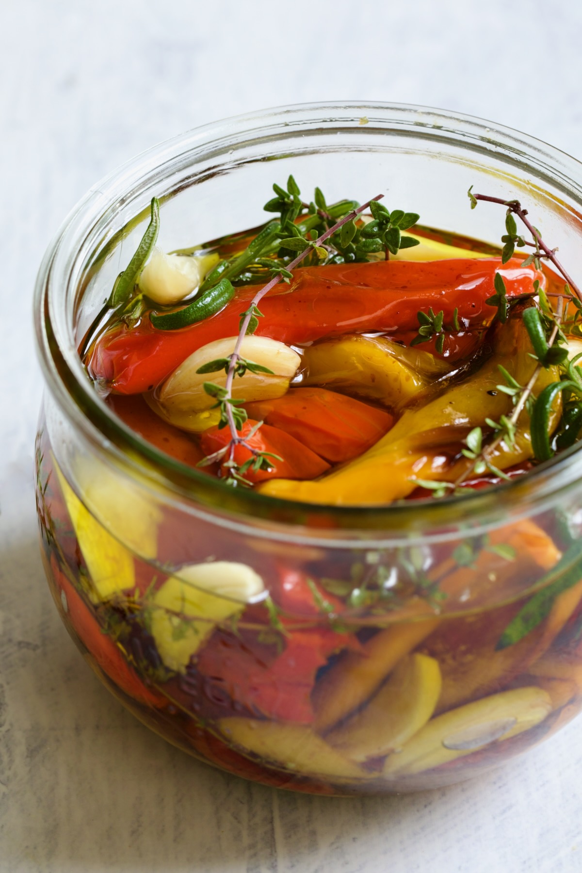 Roasted Mini Peppers in glass jar with fresh herbs and garlic.