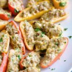 Stuffed Mini Peppers on white oval platter garnished with chopped fresh parsley.