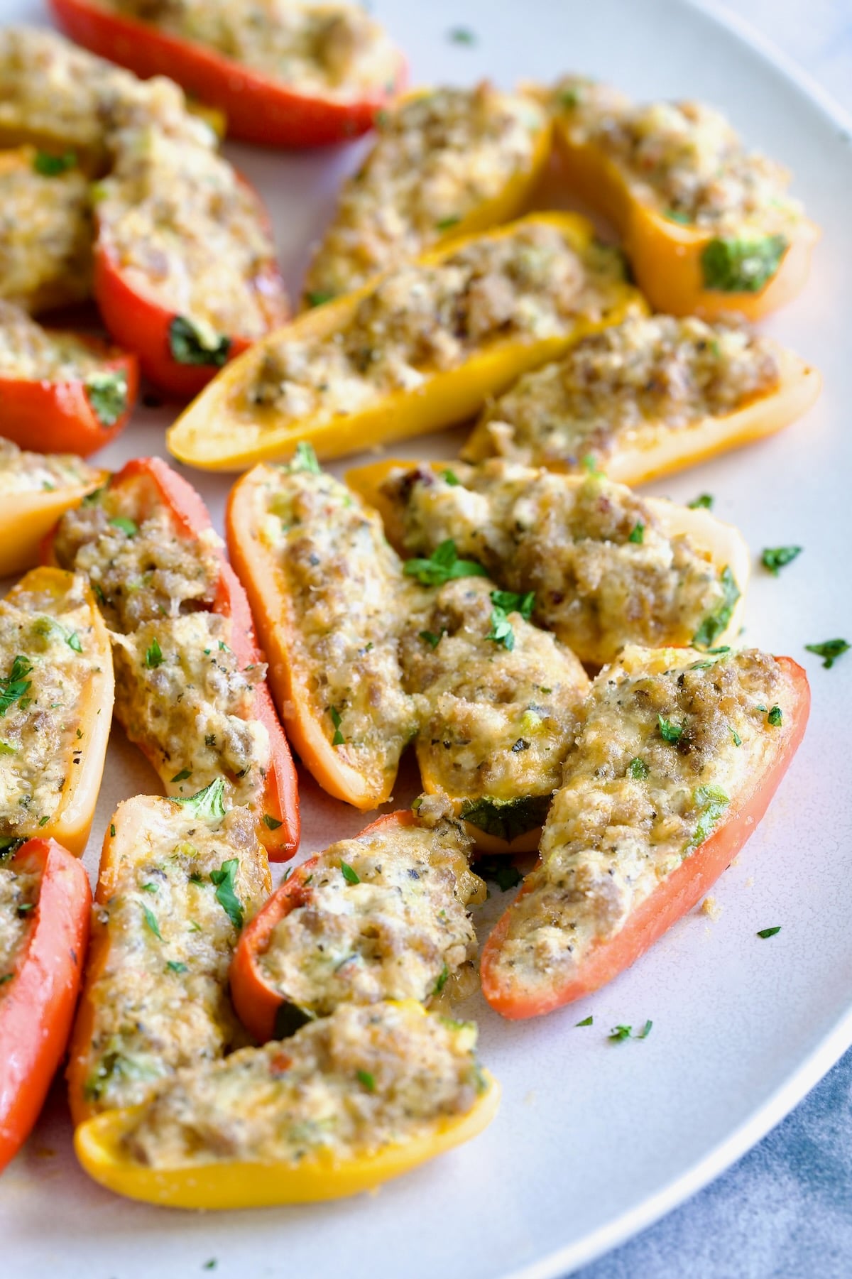 Stuffed Mini Peppers on white oval platter garnished with chopped fresh parsley.