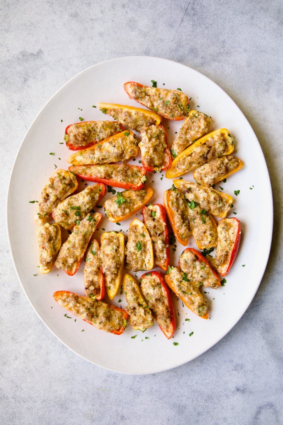 Stuffed Mini Peppers on white oval platter garnished with chopped fresh parsley.
