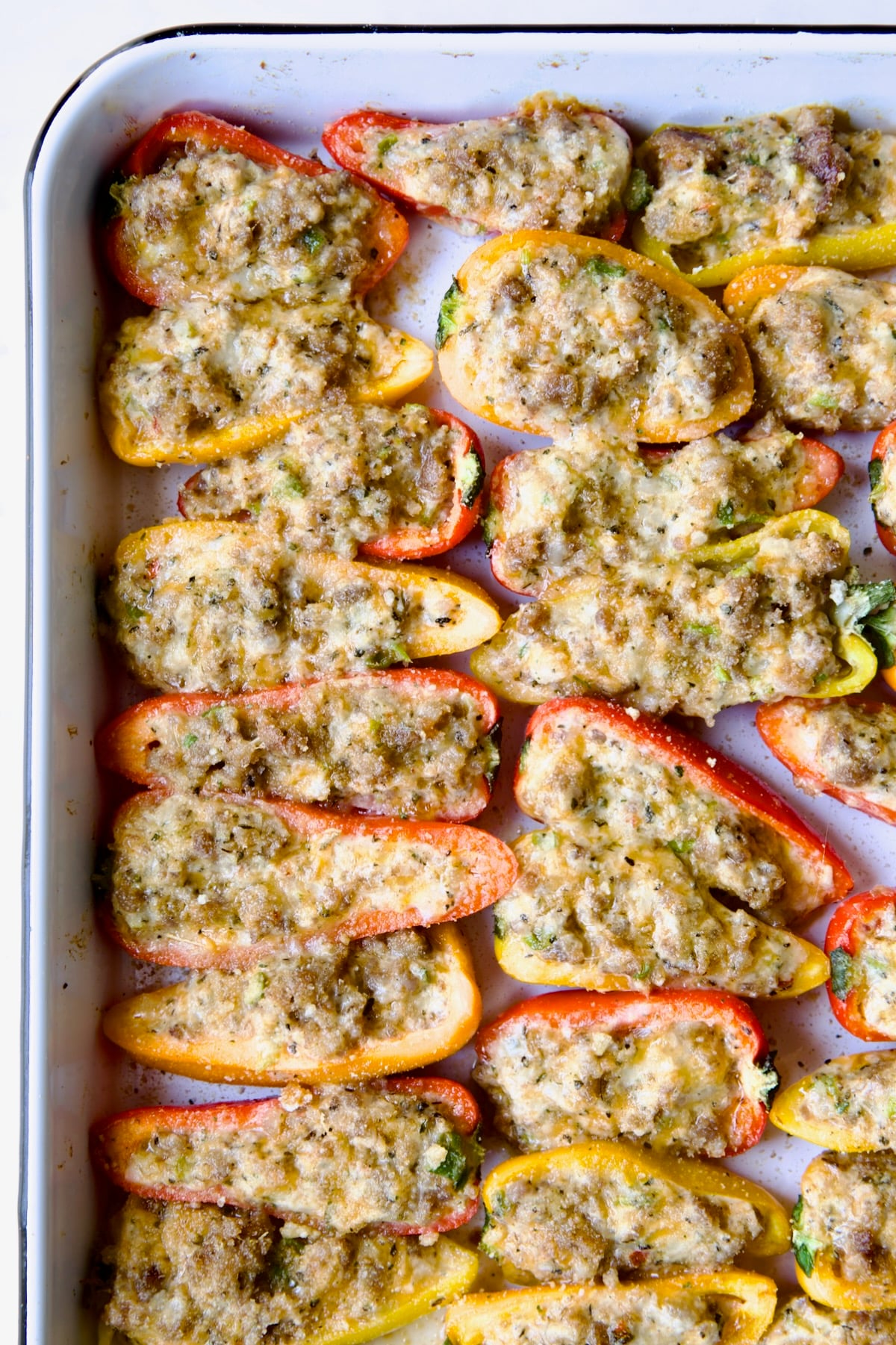 Baked Stuffed Mini Peppers on white enamel rimmed baking sheet.