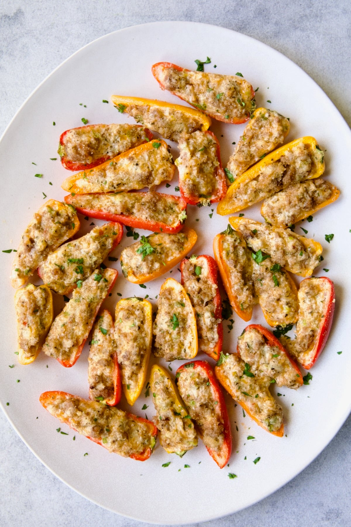 Stuffed Mini Peppers on white oval platter garnished with chopped fresh parsley.