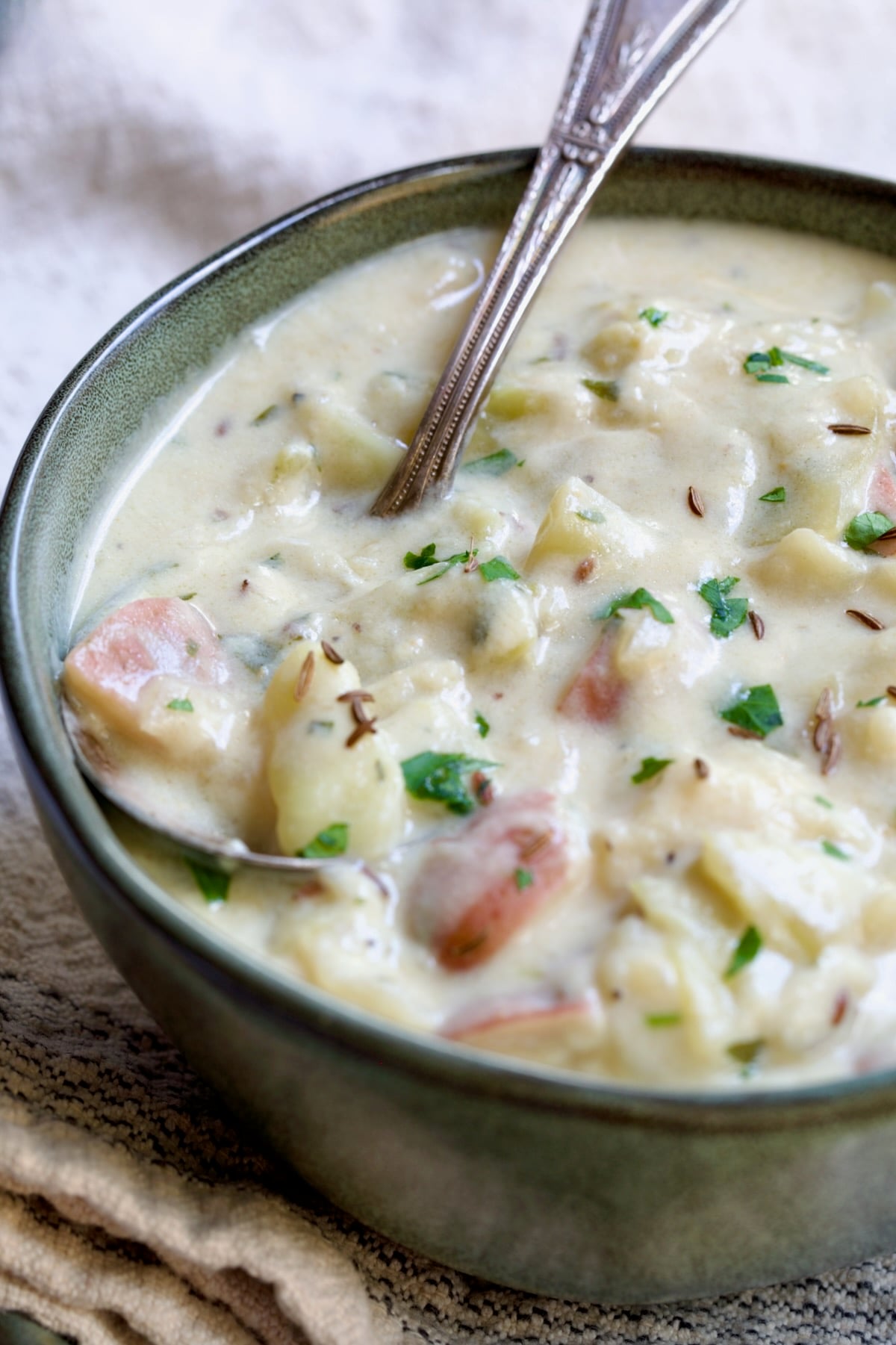 Bowl of Creamy Potato Soup in green bowl with soup spoon.
