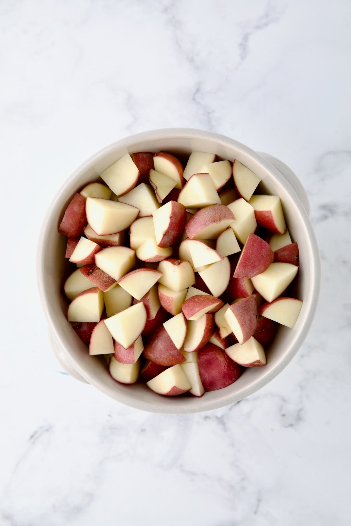 Colander full of quartered red potatoes.