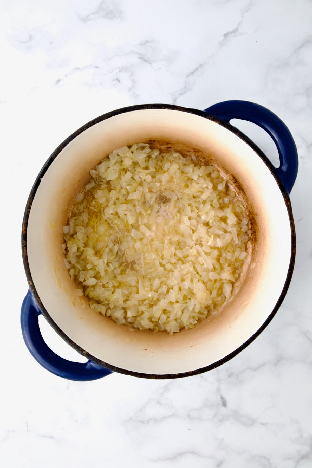 Cooked onions in blue Dutch cast iron oven.