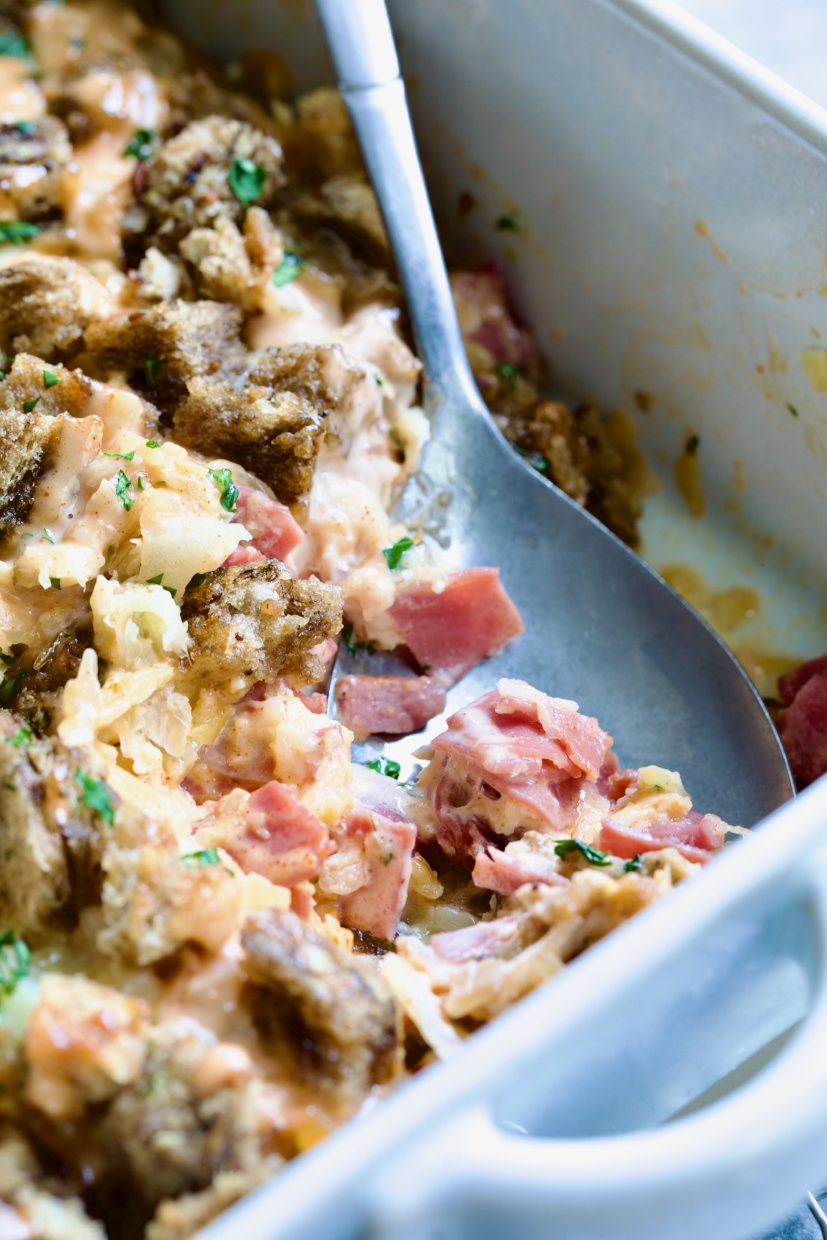 Metal serving spoon serving up some of the casserole.