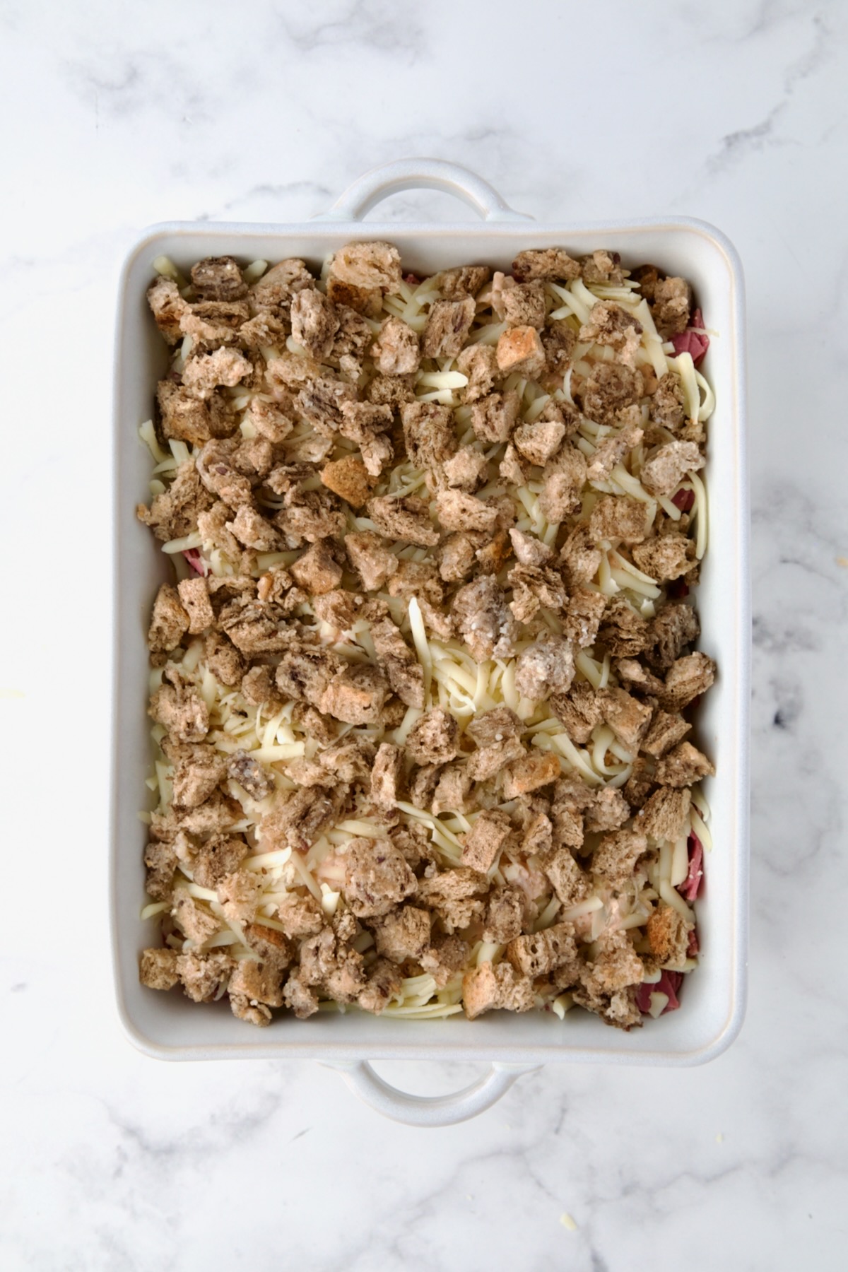 Bread cube topping on Reuben Casserole in white rectangular baking dish.