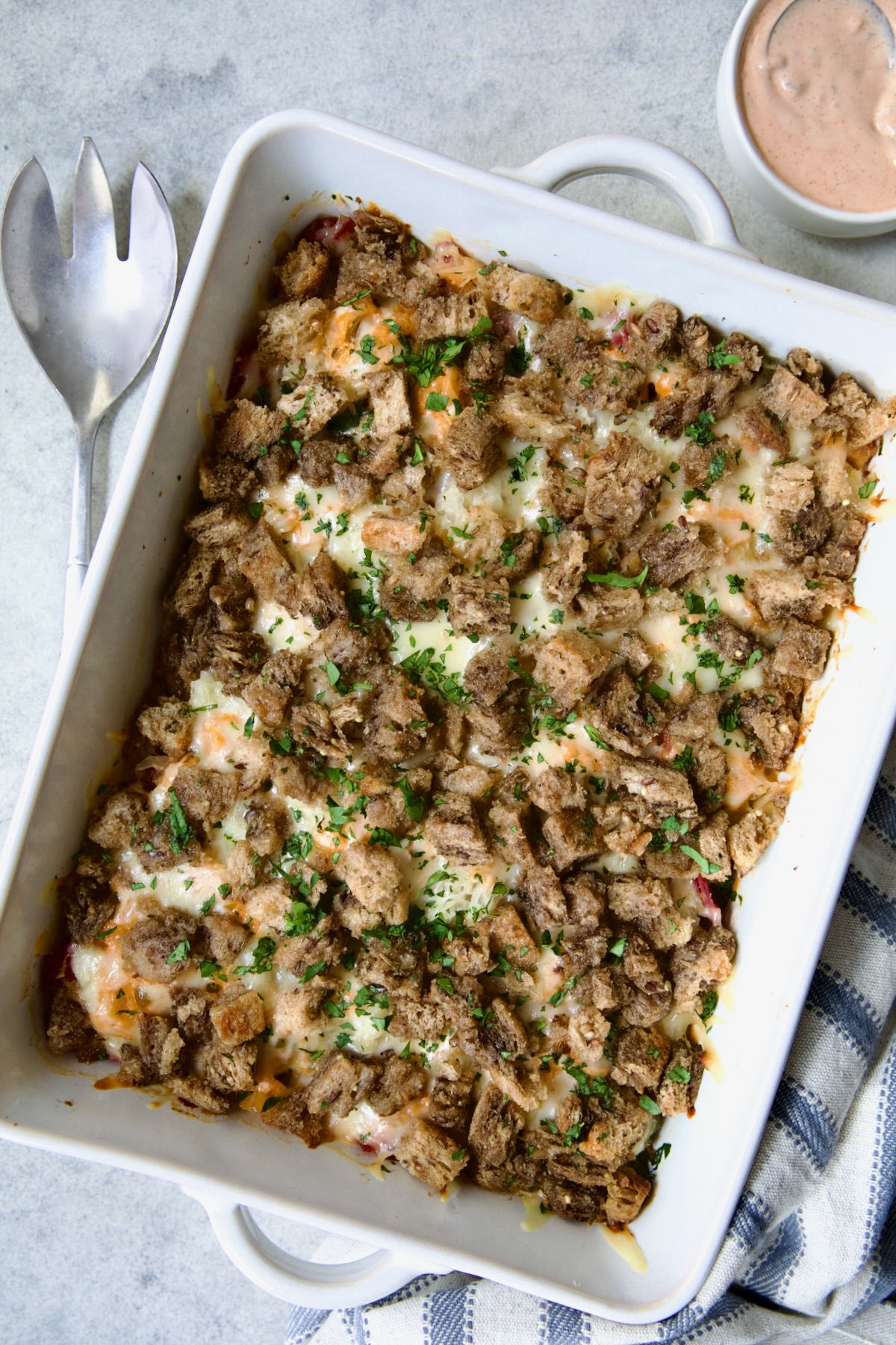 Baked Reuben Casserole in white rectangular baking dish garnished with fresh parsley.