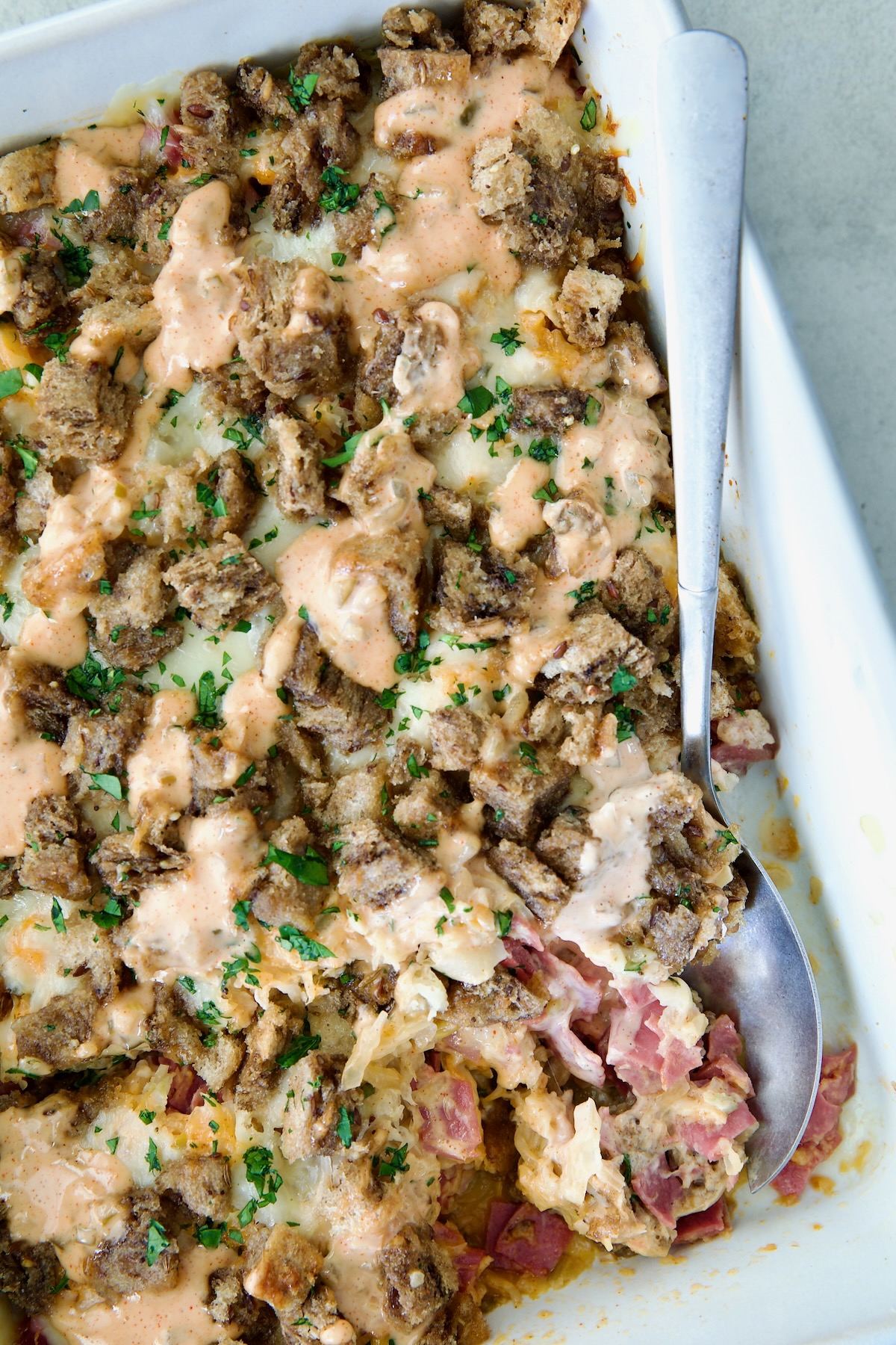 Reuben Casserole with serving spoon in white rectangular baking dish.
