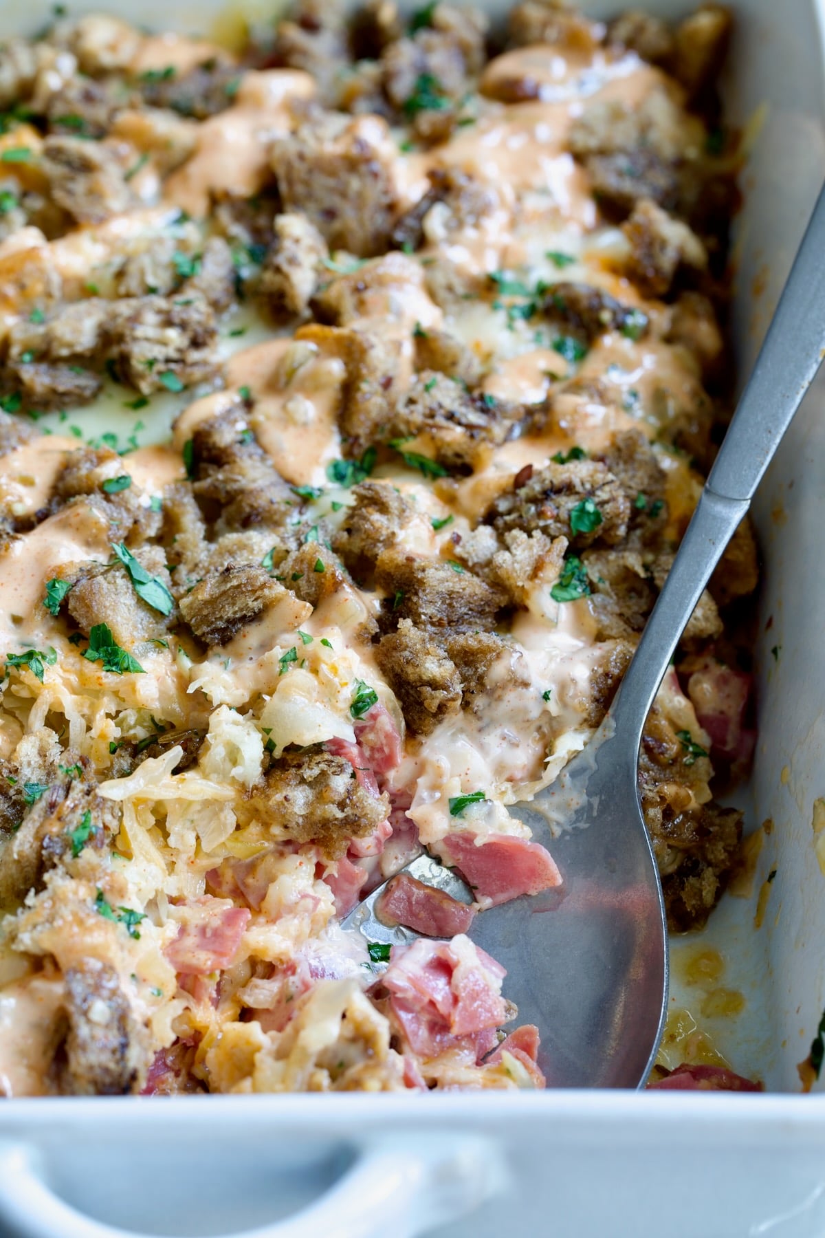 Reuben Casserole with serving spoon in white rectangular baking dish.