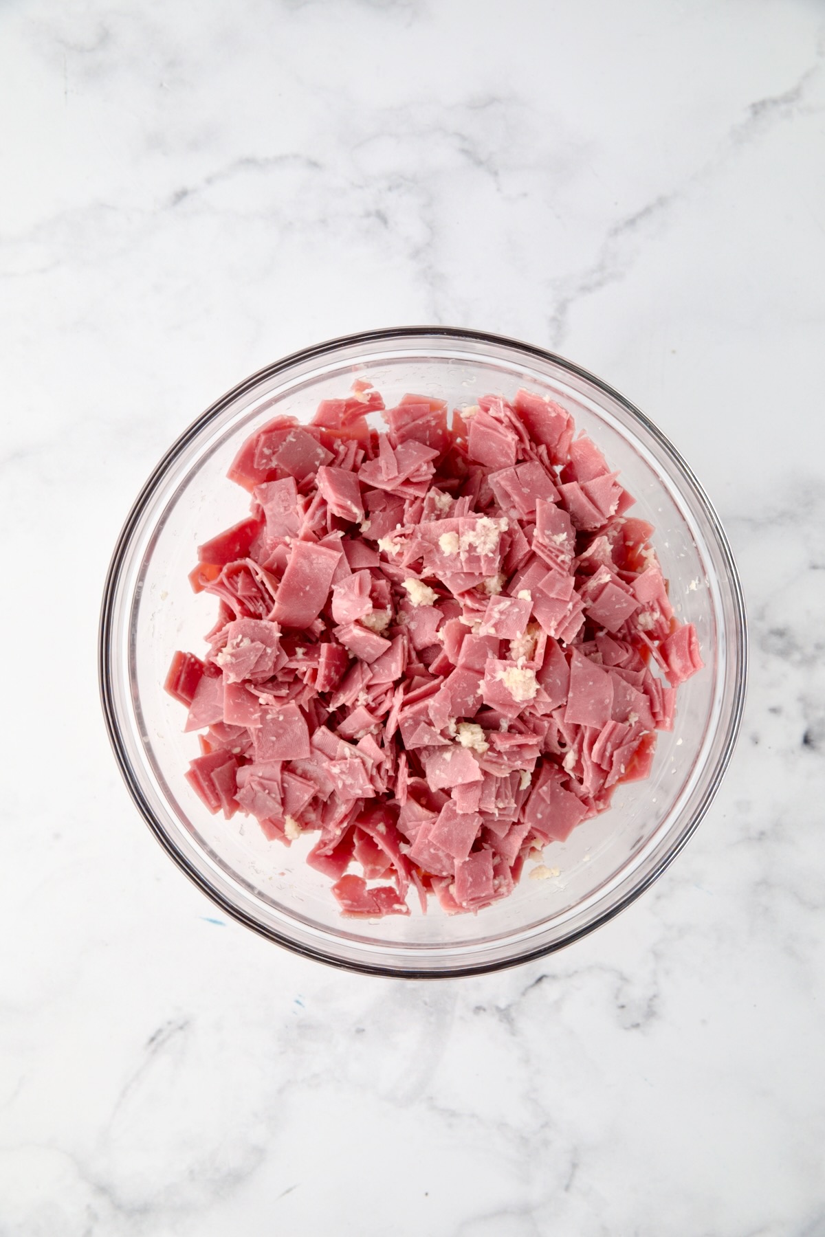 Chopped corned beef tossed with horseradish in glass bowl.