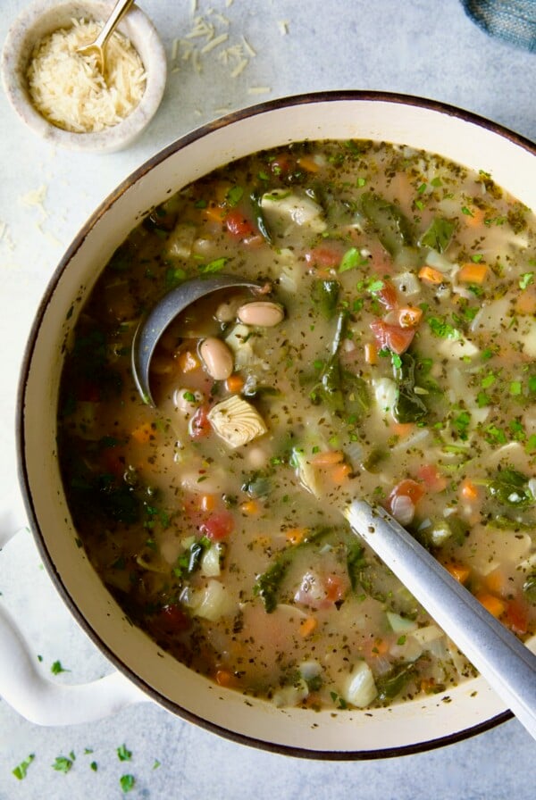 Finished soup in white Dutch oven with soup ladle.