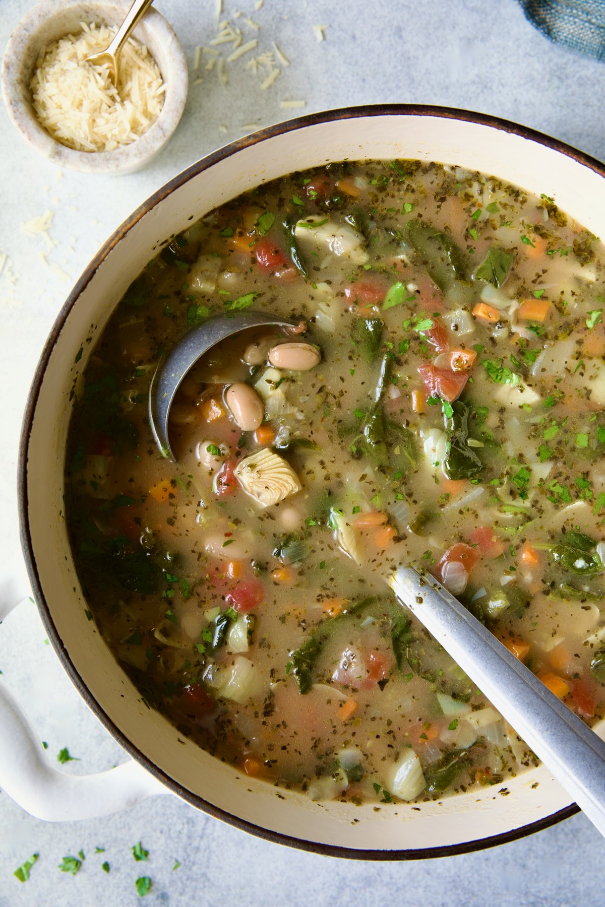 Finished soup in white Dutch oven with soup ladle.