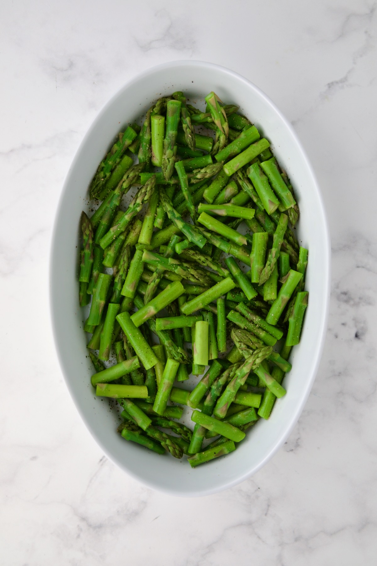 Blanched asparagus cut into pieces and placed in oval baking dish.