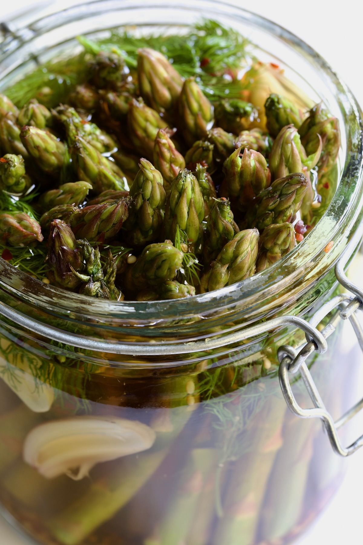 Asparagus with brine poured over it in glass jar.