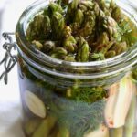 Asparagus with brine poured over it in glass jar.