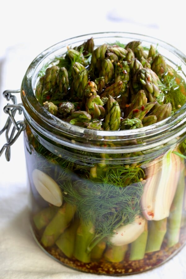 Asparagus with brine poured over it in glass jar.