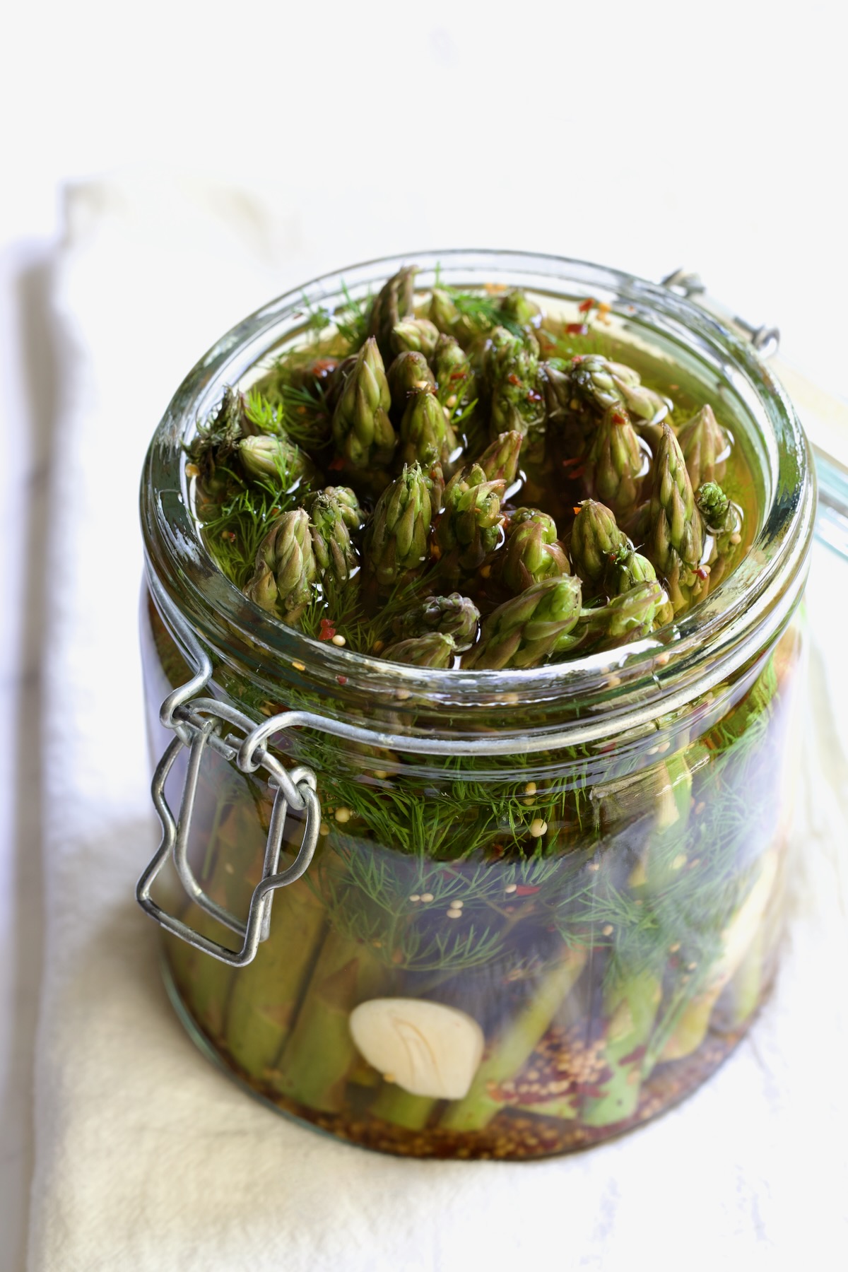 Pickled Asparagus with brine poured over it in glass jar.