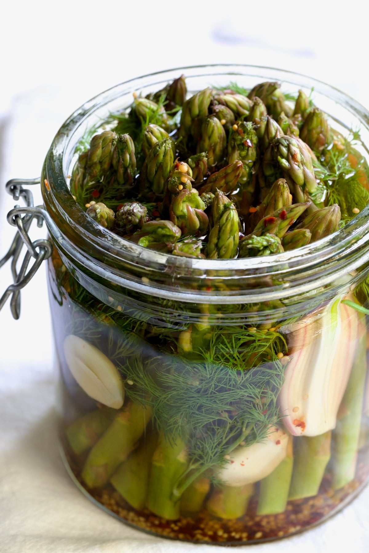 Asparagus with brine poured over it in glass jar.