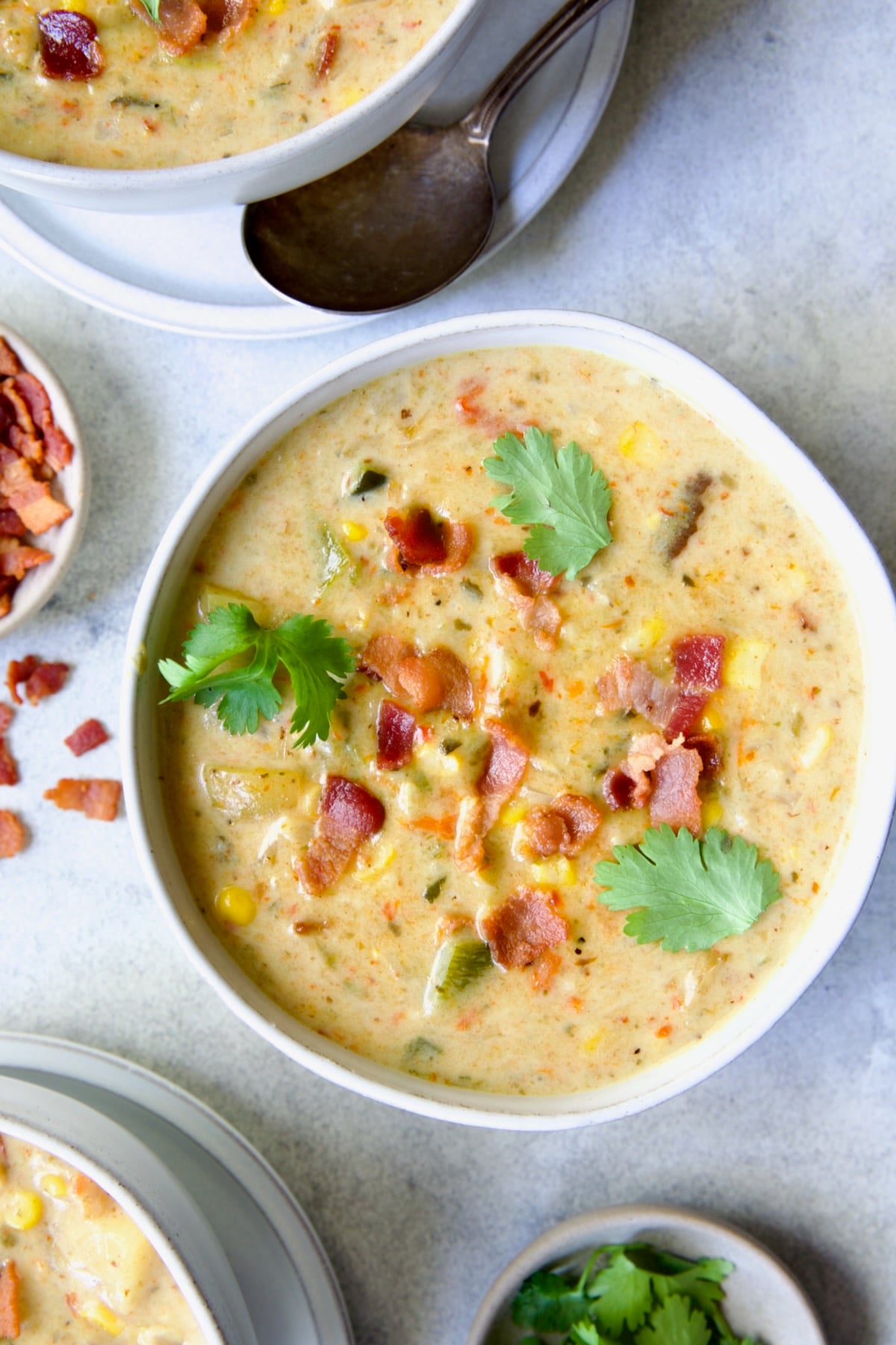 Roasted Poblano Corn Chowder in white bowl garnished with cilantro sprigs.